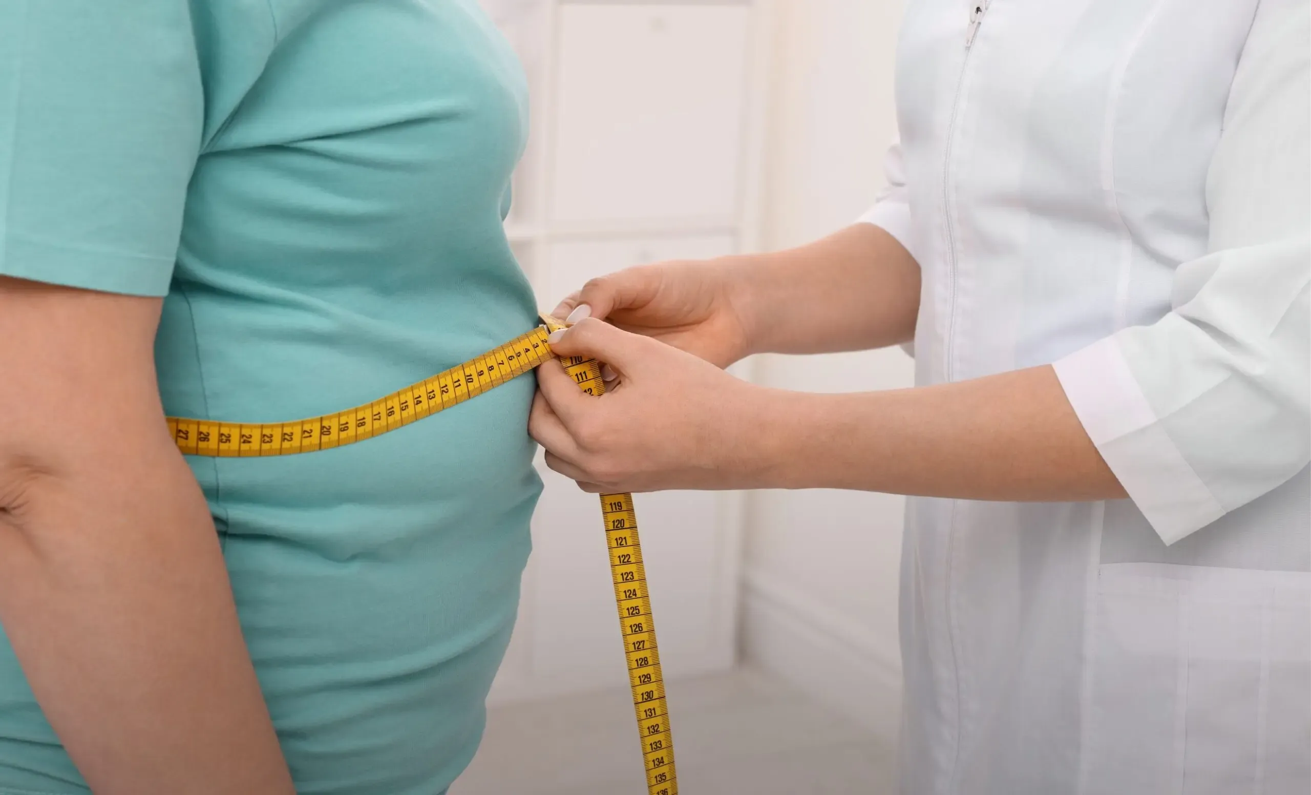 Clinician measuring a patient's waist circumference during an obesity treatment consultation