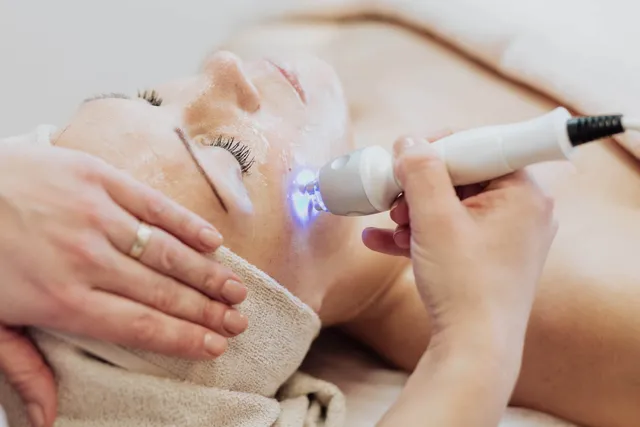 Therapist applying a light-therapy device to a patient's face during a skin rejuvenation treatment